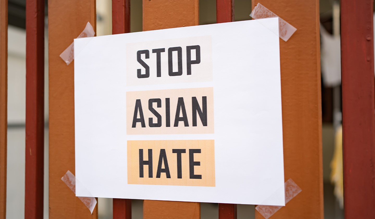 Image of a fence with a piece of paper taped to it that says Stop Asian Hate