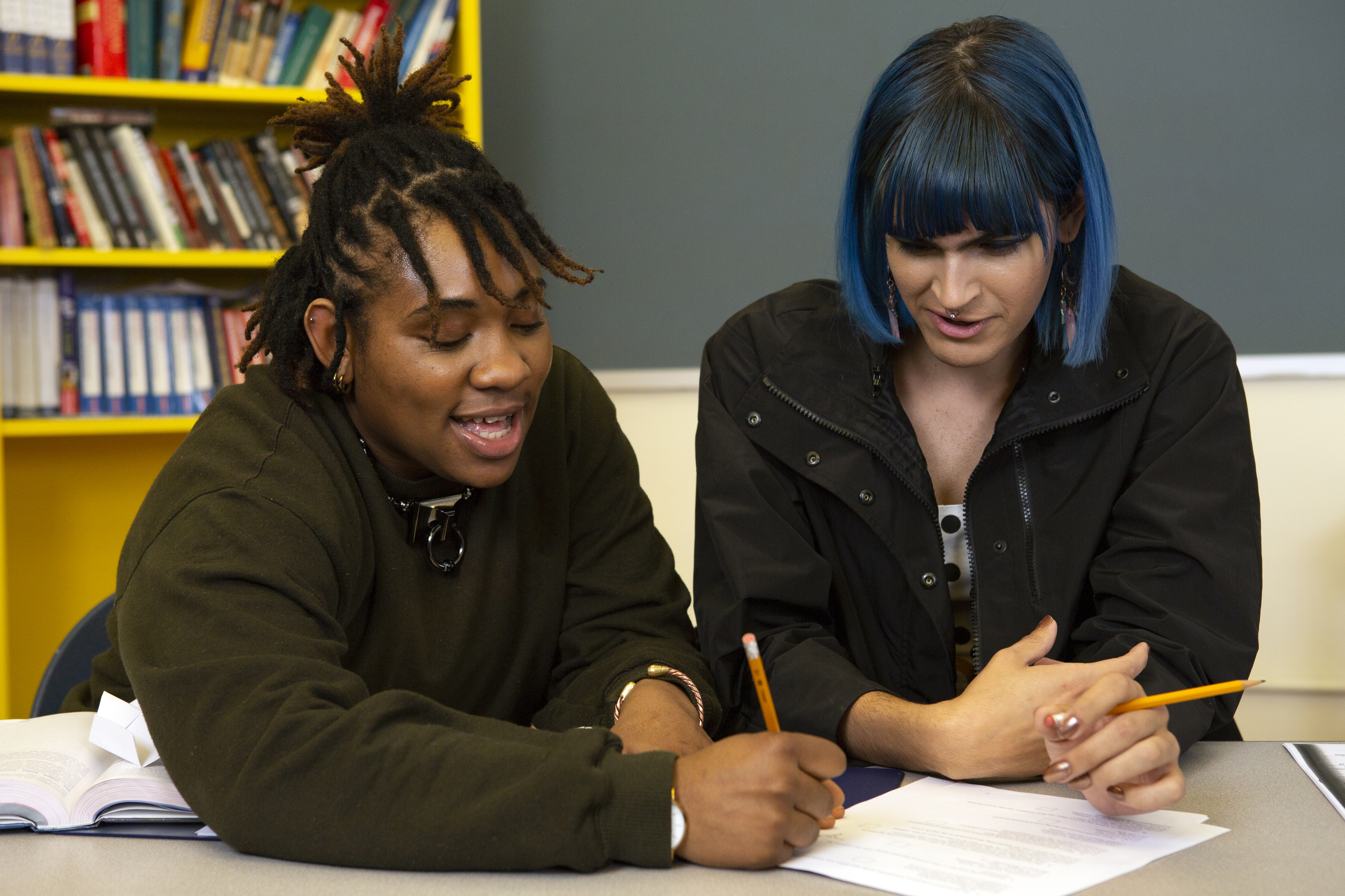 Two non-binary students doing work together in class.
