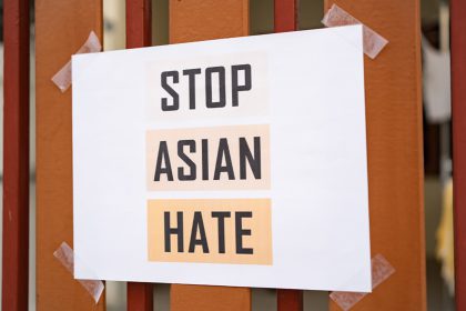 Image of a fence with a piece of paper taped to it that says Stop Asian Hate